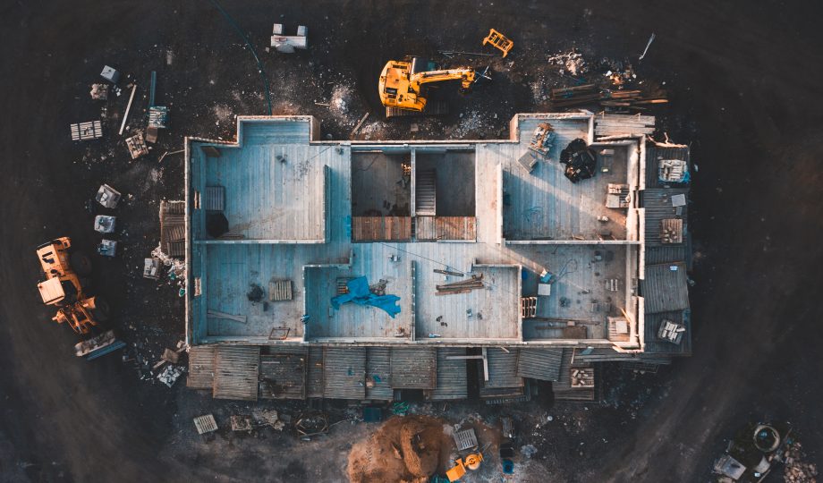 Aerial top down shot of a house frame on a construction site surrounded by mud Aerial top down shot of a house frame on a construction site surrounded by mud